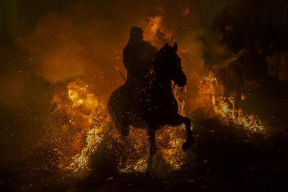 A man rides his horse through flames during the 